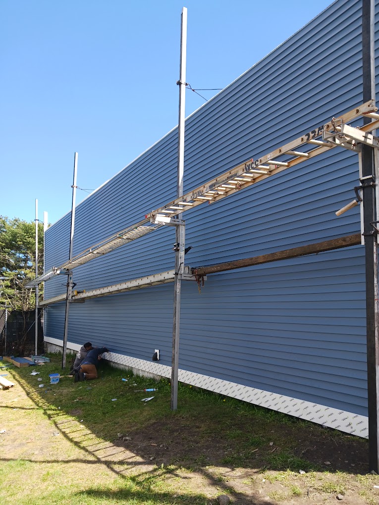 Blue siding installation with scaffolding